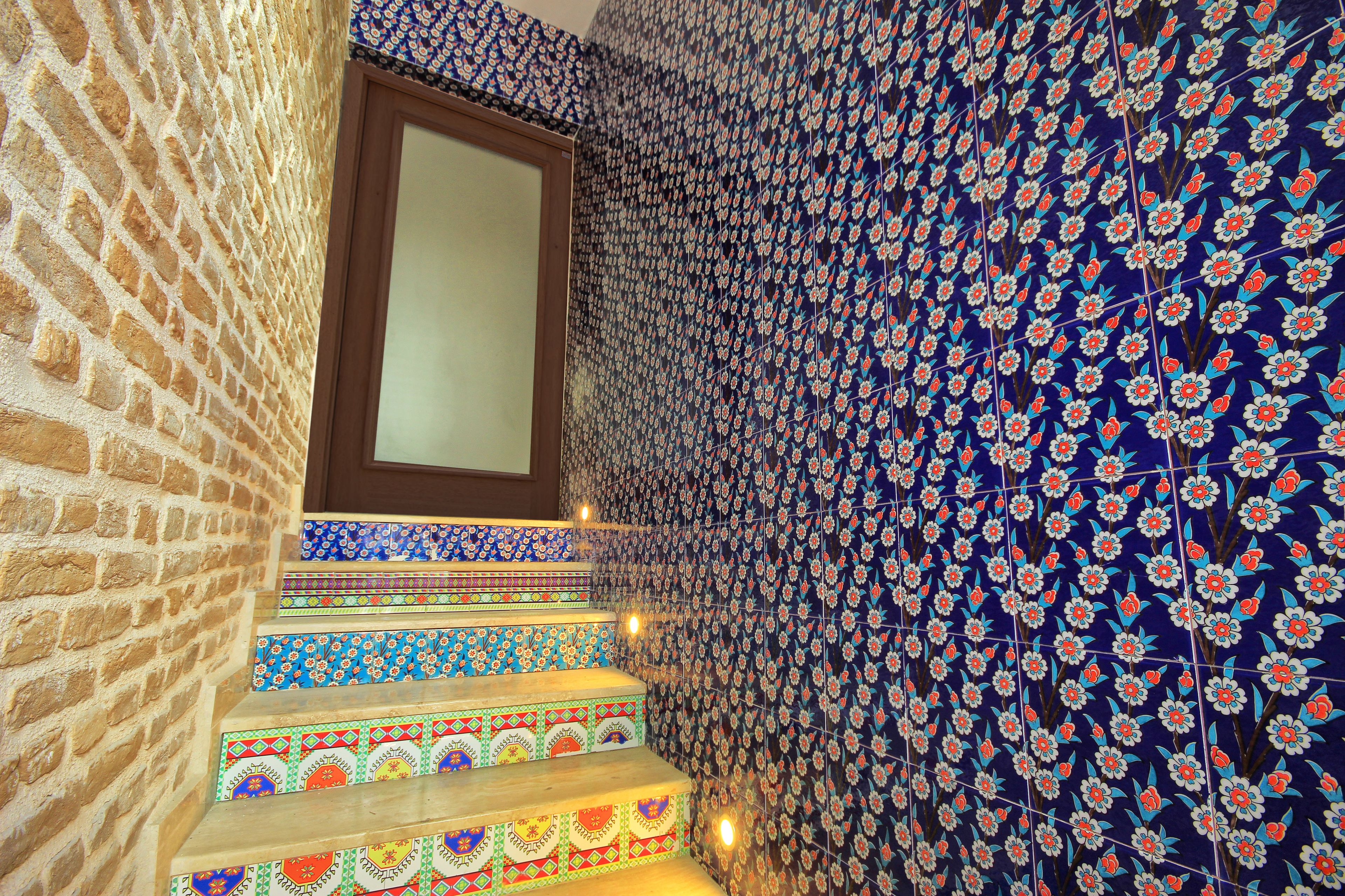 A staircase with colorful, patterned tiles and a brick wall.