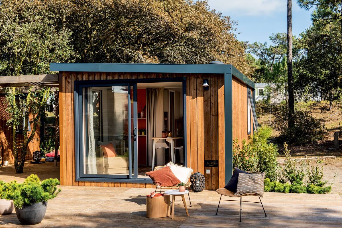 Eine kleine Holzhütte mit Glastür, einem Tisch mit Stühlen und einem Blumentopf.