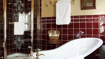 Une salle de bain avec une baignoire sur pieds, une douche à parois de verre et un meuble-lavabo avec un miroir et un porte-serviettes.