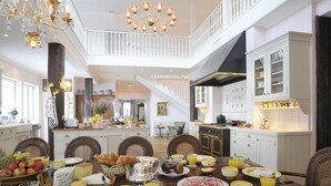 Une salle à manger spacieuse avec un plafond haut, un lustre et un escalier menant à un niveau supérieur.