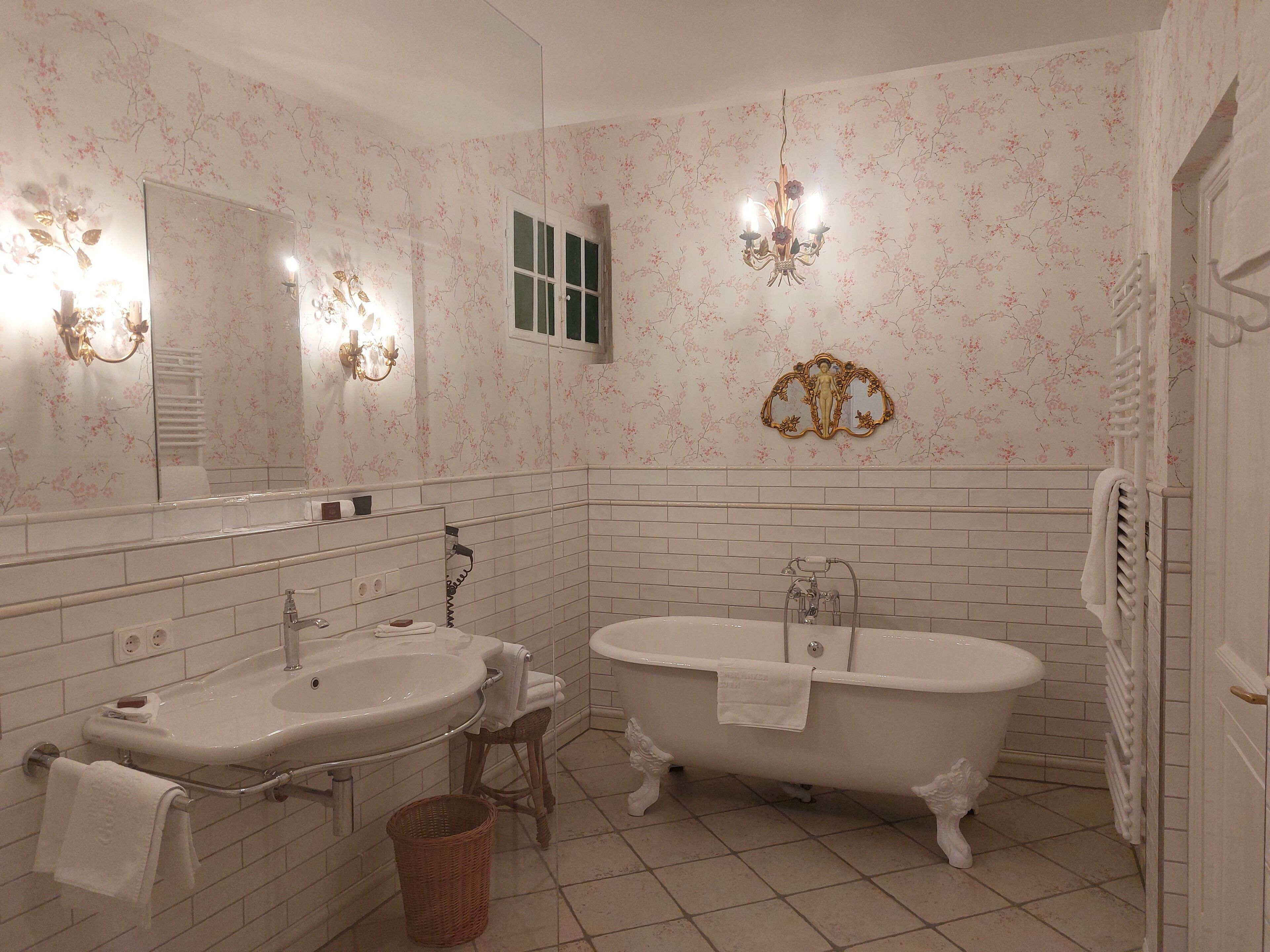 A bathroom with two sinks, a bathtub, a mirror, and a chandelier.