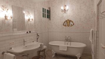 A bathroom with two sinks, a bathtub, a mirror, and a chandelier.