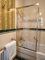 A bathroom with a glass-enclosed shower, a towel rack, and decorative tiles.
