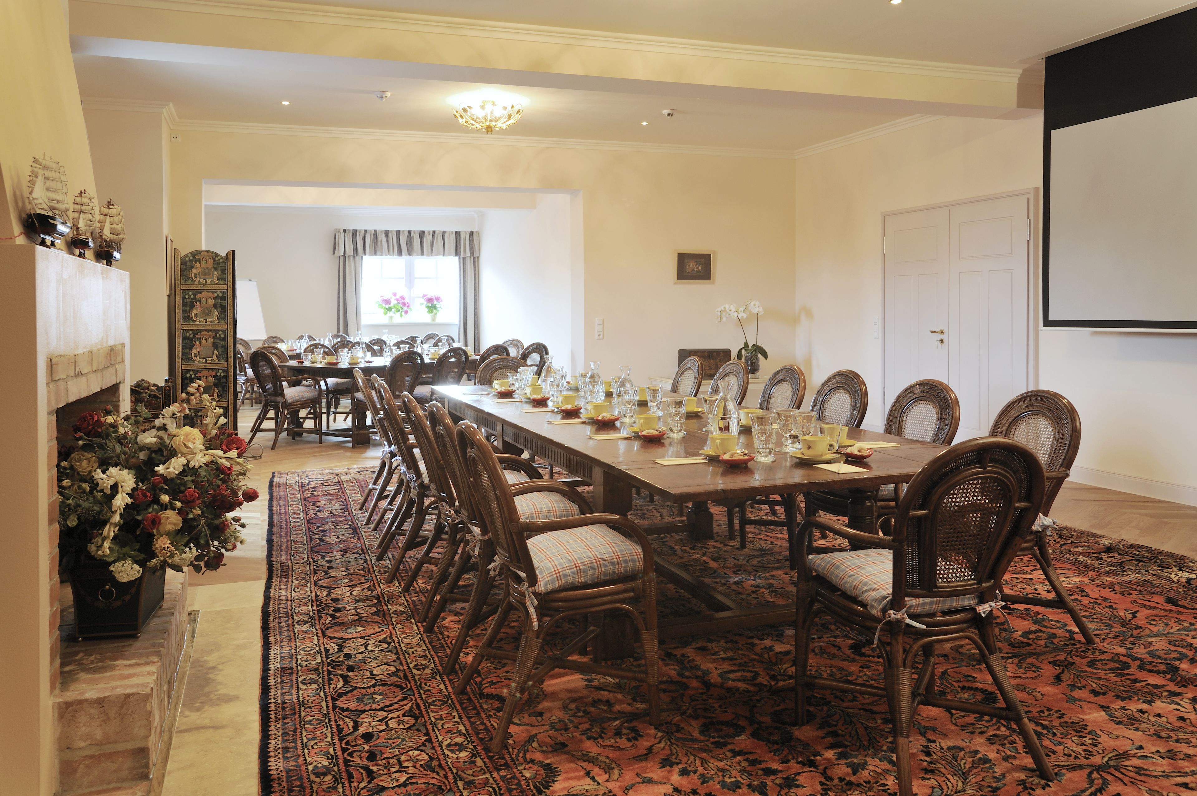 A formal dining room with a long table, chairs, and a fireplace.