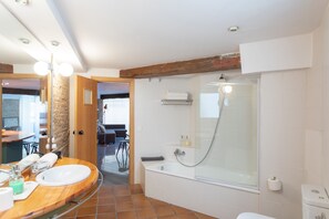 Un baño moderno con tocador de madera, ducha con mampara de vidrio y inodoro a la vista.