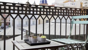 A balcony with a metal railing, a small table with potted plants, and a green chair. - Bubuflats Mossen (Valencia)