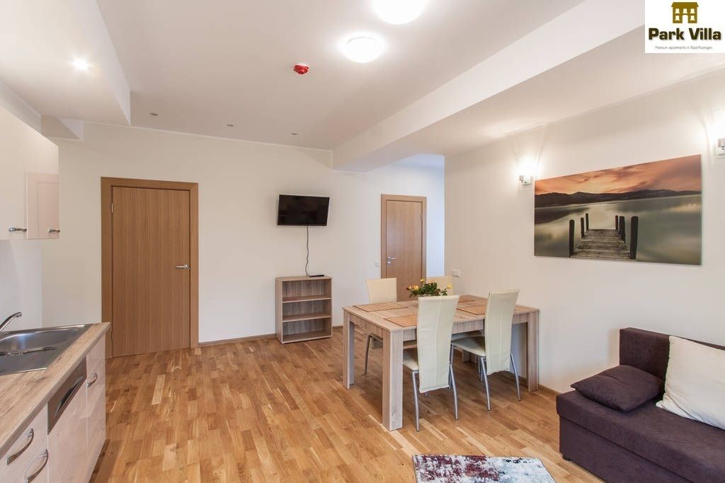 Ein modernes Wohnzimmer mit einem Holzespeisetisch, einer Couch und einem an der Wand montierten Fernseher.