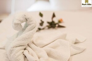 Een keurig opgevouwen witte handdoek op een bed, met het logo van Park Villa rechtsboven.