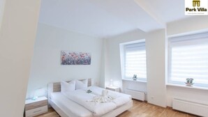 Un dormitorio moderno con una cama grande, mesitas de noche y una ventana con persianas.
