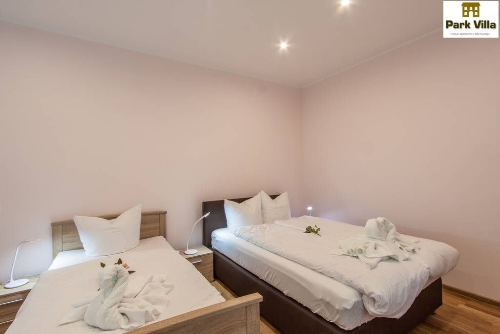 Habitación de hotel con dos camas, una mesita de noche, una lámpara y una toalla sobre la cama.