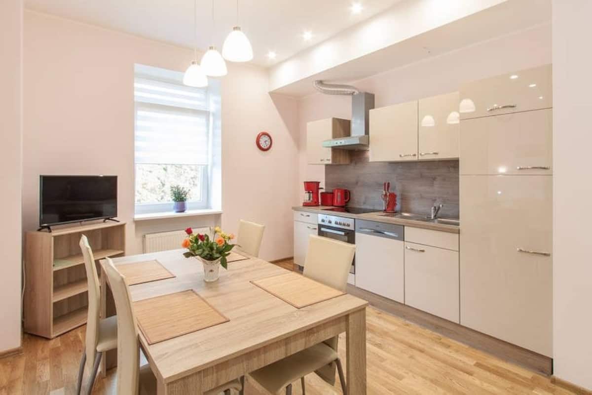 Een moderne keuken met witte kastjes, een ingebouwde oven en een rode koffiezetapparaat.