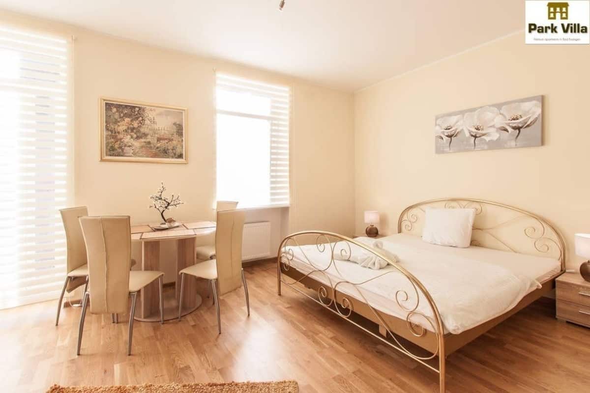 Een slaapkamer met een bed, een bureau, stoelen en kunstwerken aan de muur.