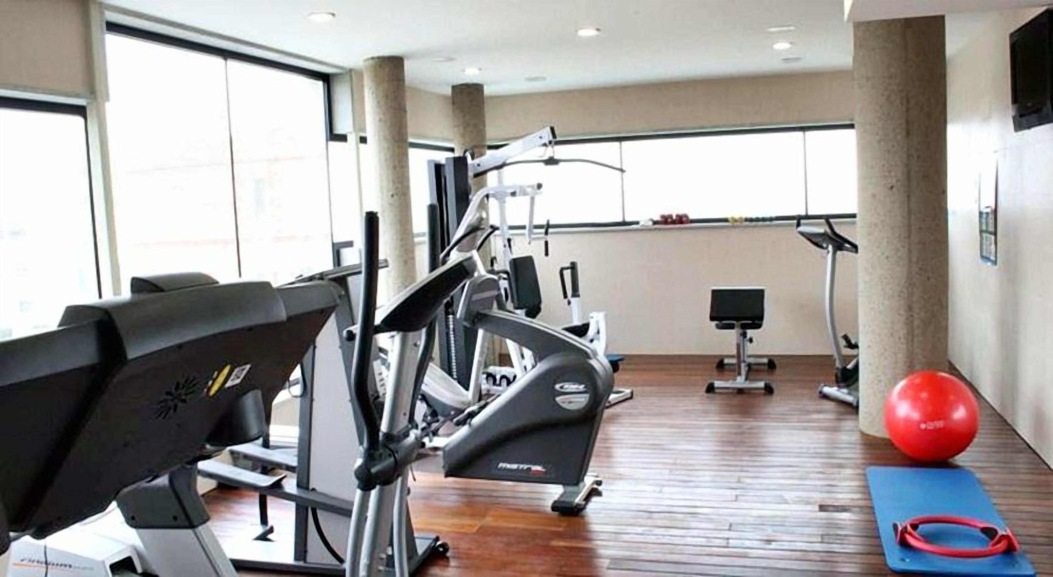 Una palestra con macchinari cardio, un vogatore e palle da ginnastica.