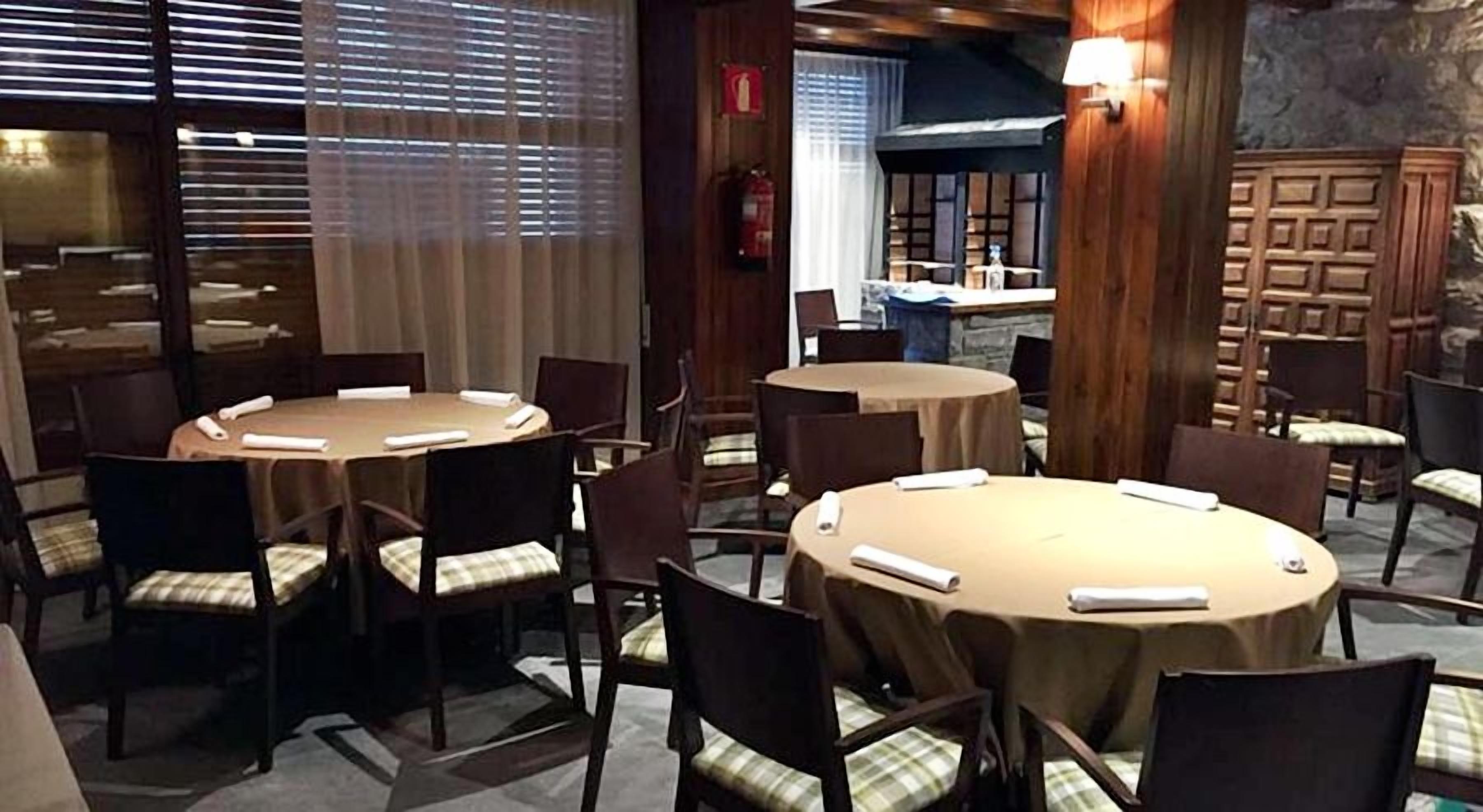 A conference room with round tables and chairs, a fire extinguisher, and a stone wall in the background.
