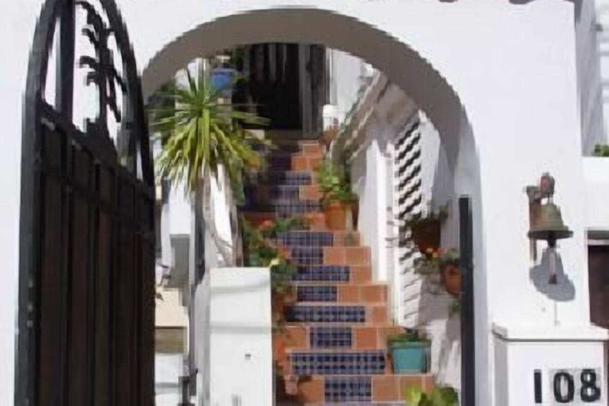 A white building with a tiled staircase leading to a gated entrance.