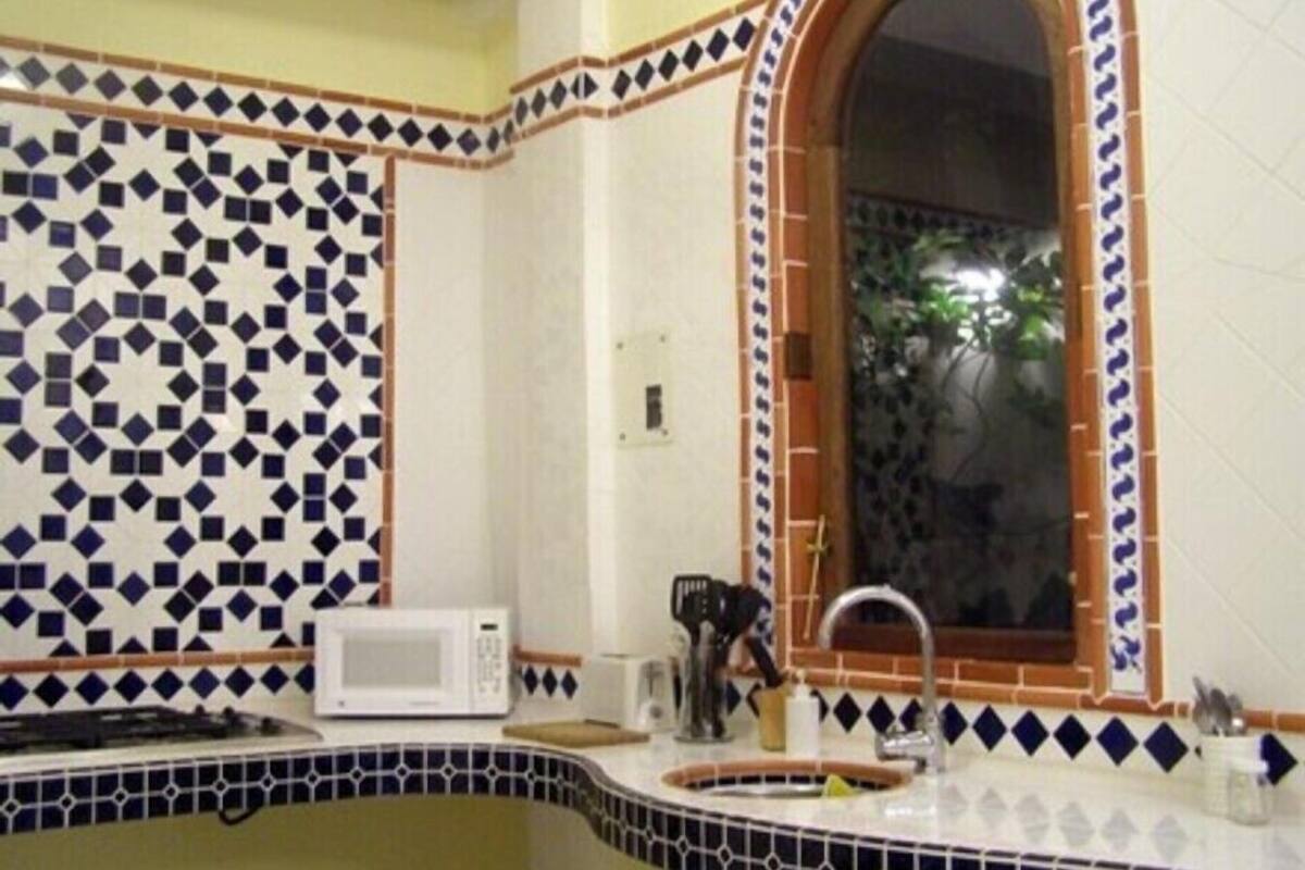 A kitchen with a microwave, sink, and tiled backsplash.