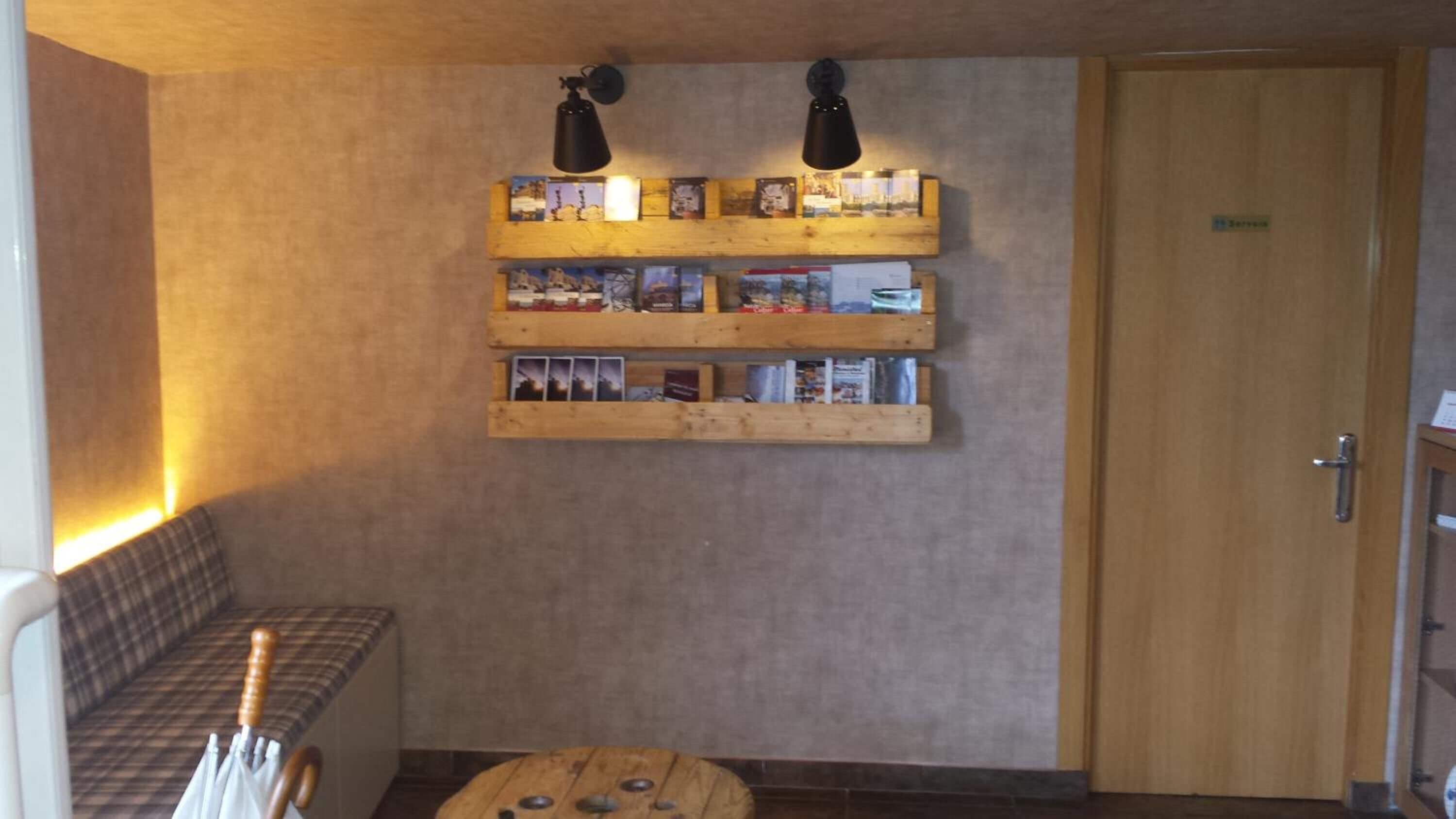 A cozy room with a wooden bench, a small table, and a wall-mounted shelf with various items.