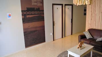 A hotel lobby with a large mural, two doors, a brown leather sofa, and a small white table.