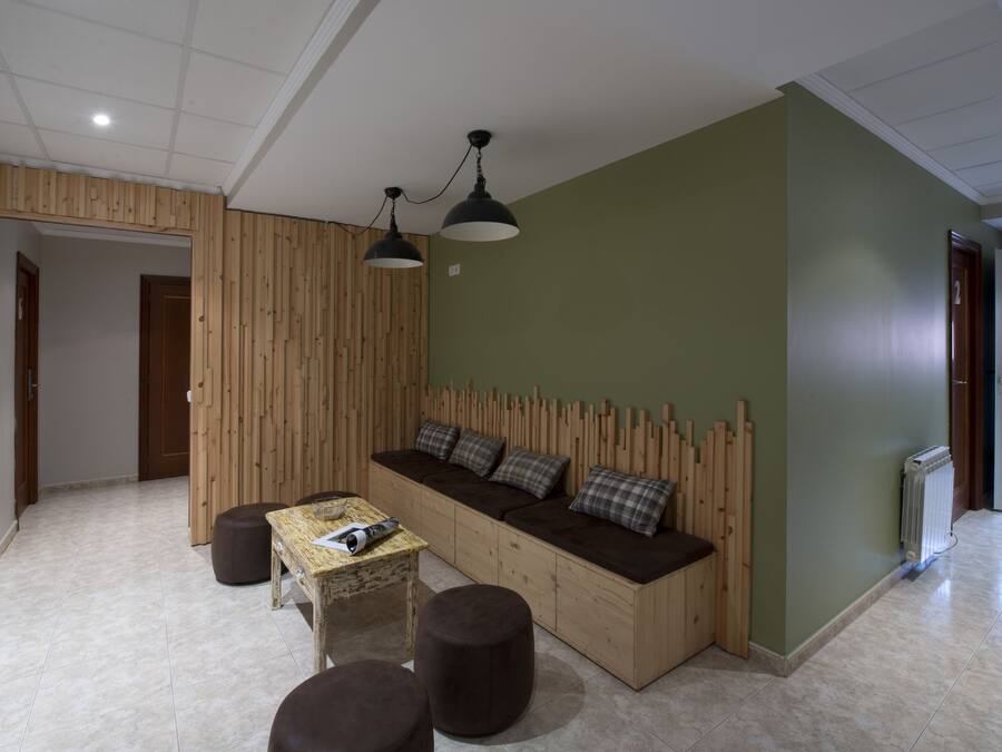 A modern living room with a built-in sofa, a small table, and two ottomans.