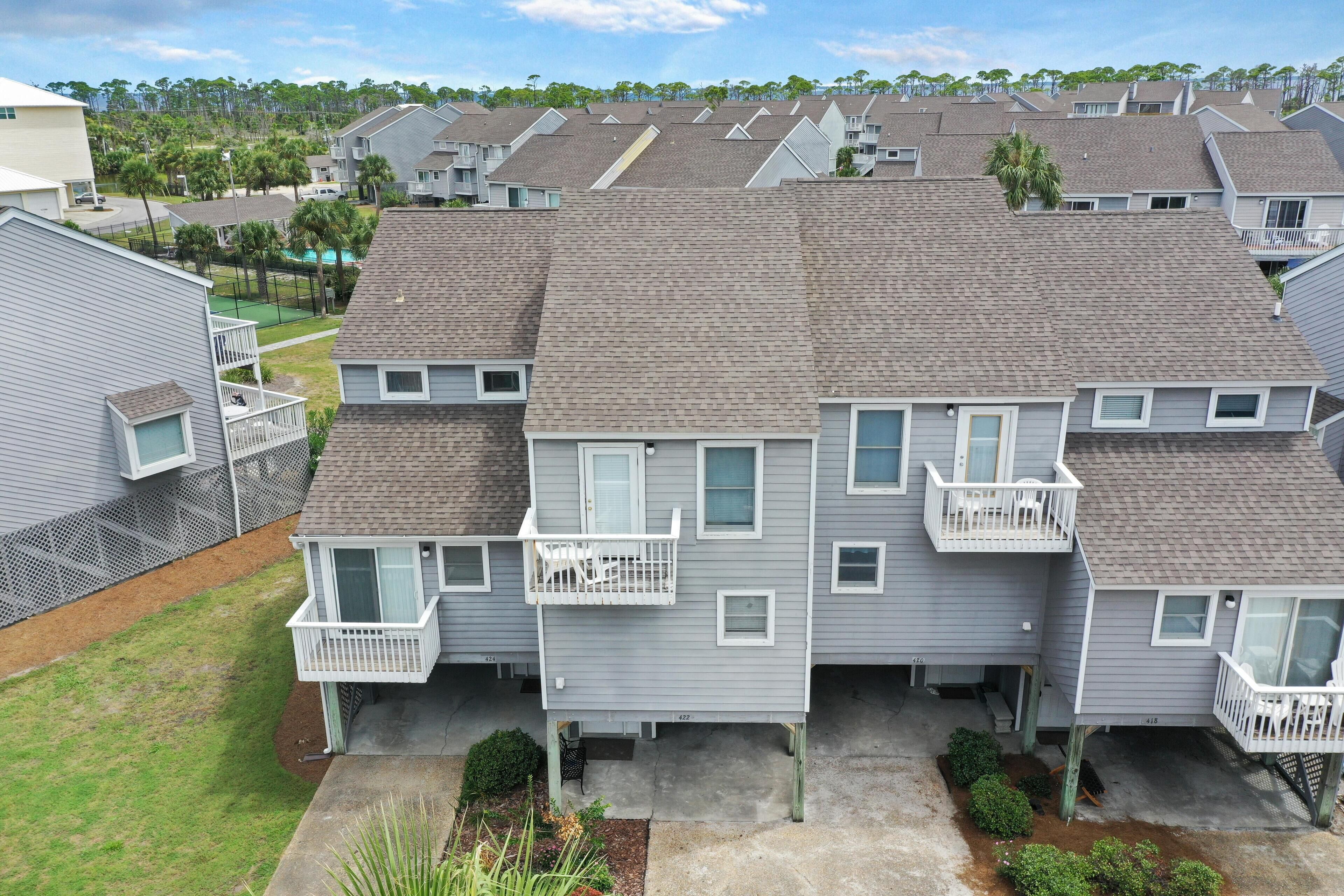 A multi-story residential building with a grey exterior, multiple balconies, and a small front yard.