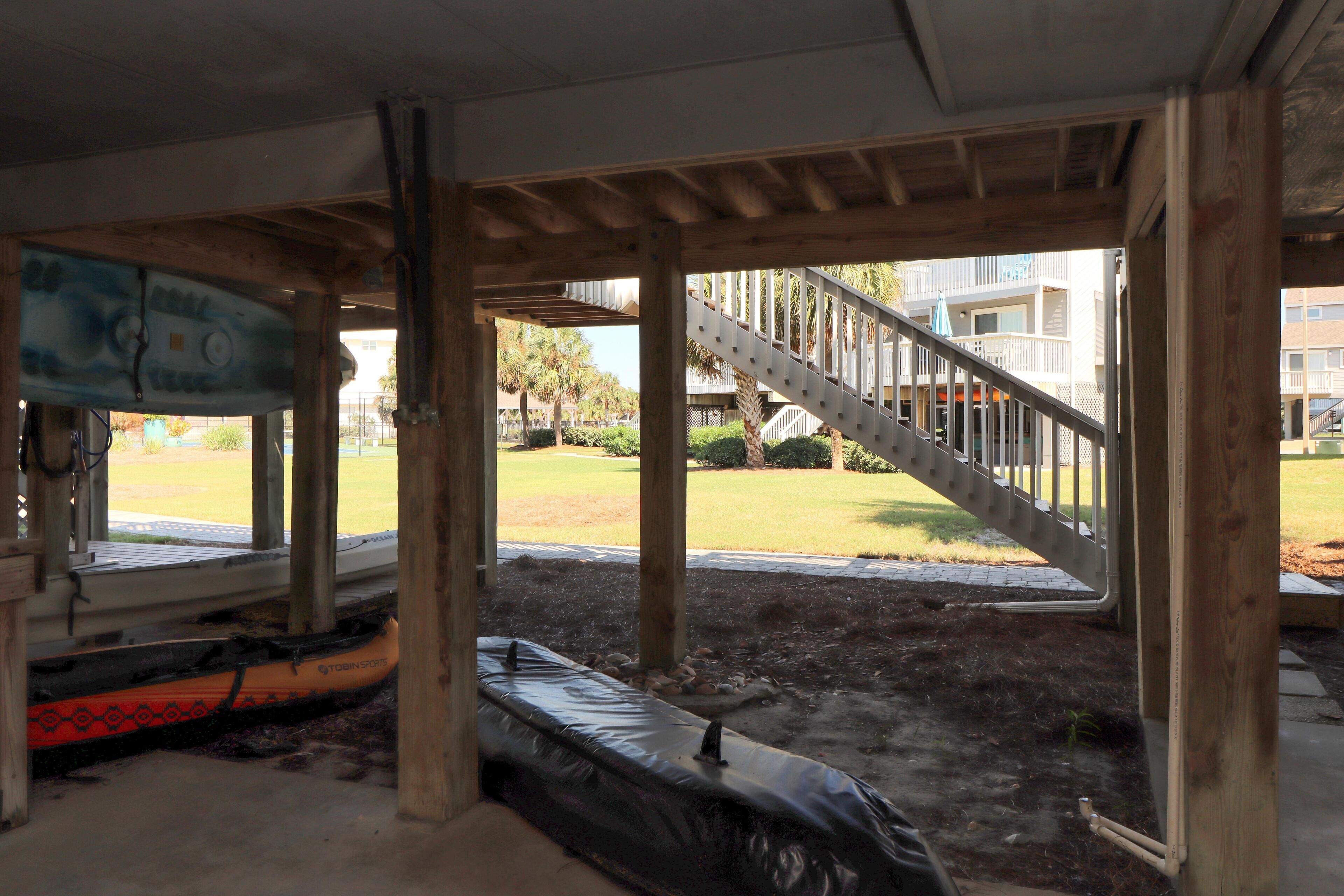 A partially constructed building with exposed wooden beams and a view of a residential area with a staircase and a lawn.
