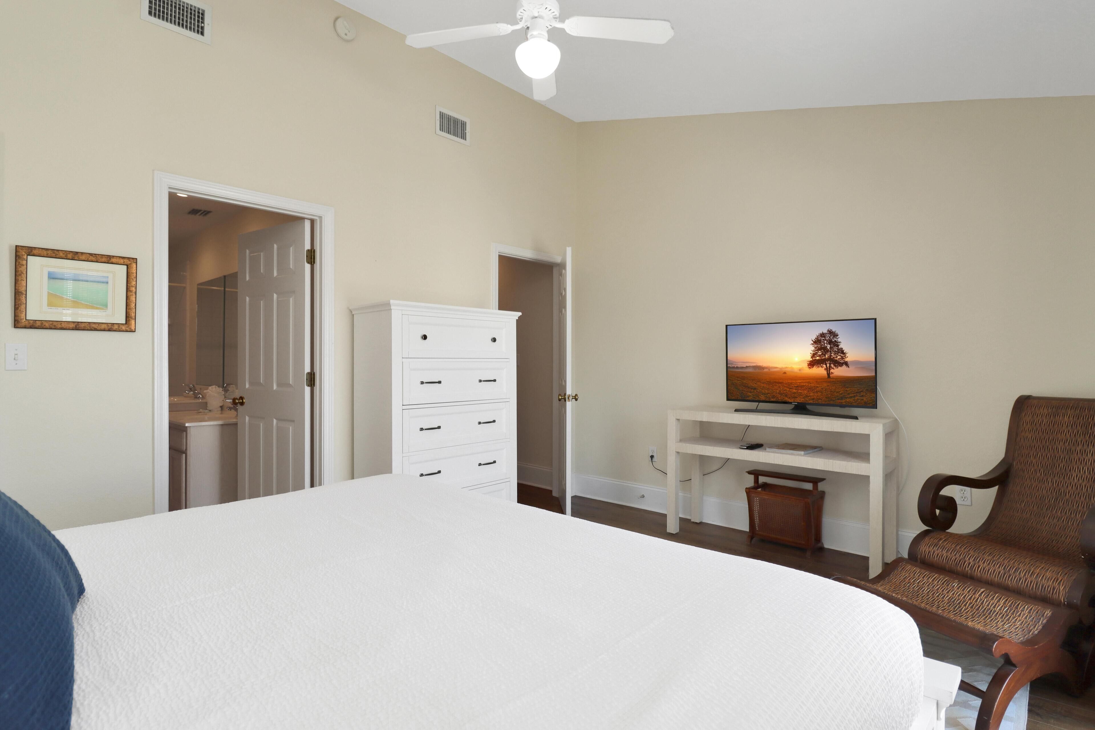 Une chambre à coucher avec un lit, un téléviseur posé sur un meuble, une chaise et une armoire.
