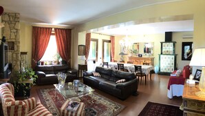 Un salon doté d’une cheminée, de canapés en cuir, d’une table basse en verre et d’un coin repas avec une table et des chaises.
