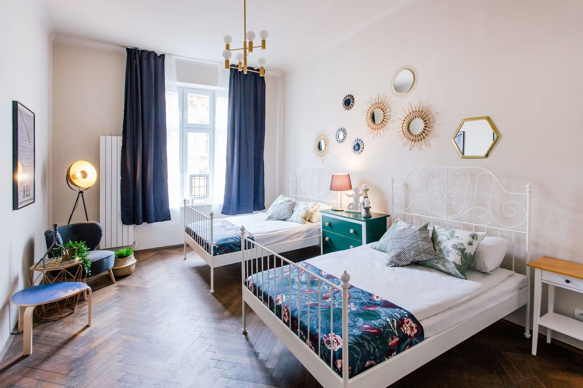 Une chambre avec deux lits, un bureau, une chaise et une fenêtre avec des rideaux.