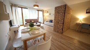 Een moderne woonkamer met een eethoek, een bank, een lamp en een muur met gestapelde houtblokken.