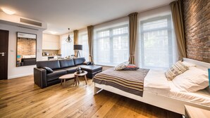 Een moderne woonkamer met een bank, salontafel en een bed met een gebedecoreerde deken.