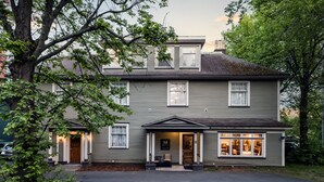 A two-story building with a front porch, a sign with the letter 'M', and a visible storefront with glass doors. - Monroe House Executive Suites (St. John's)