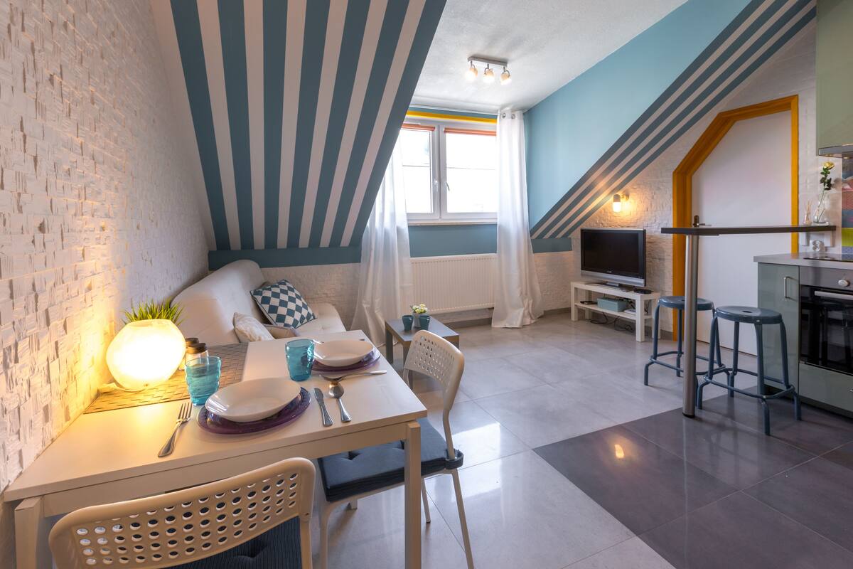 A compact living space with a dining area, kitchenette, and a TV.