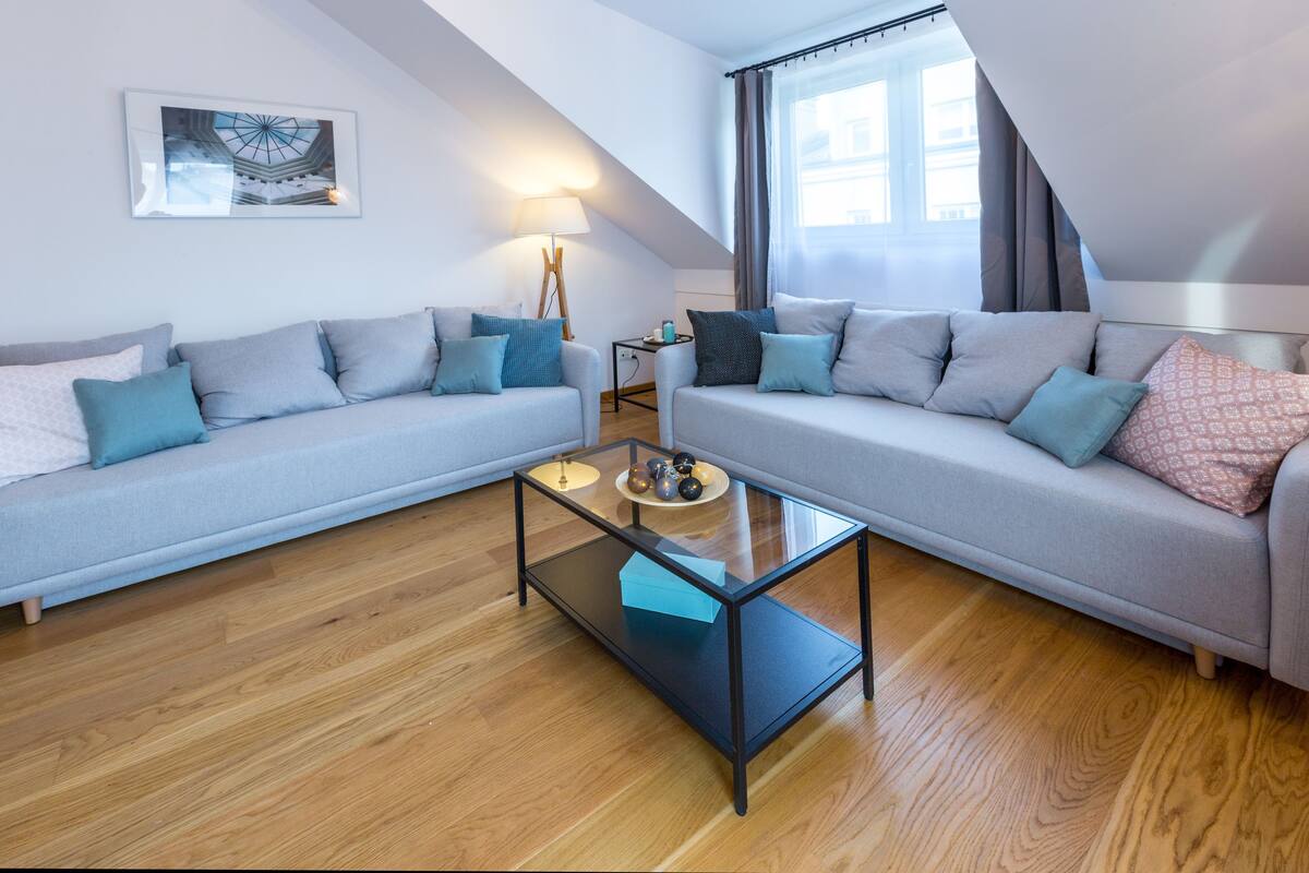 A modern living room with two grey sofas, a glass coffee table, and a lamp.