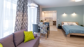 A modern apartment with a living area, a dining table, a kitchen, and a bedroom. - Friendhouse Apartments - Train Station Area (Kraków)