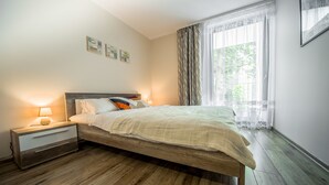 Een slaapkamer met een houten bed, een nachtkastje met een lamp en een raam met gordijnen.