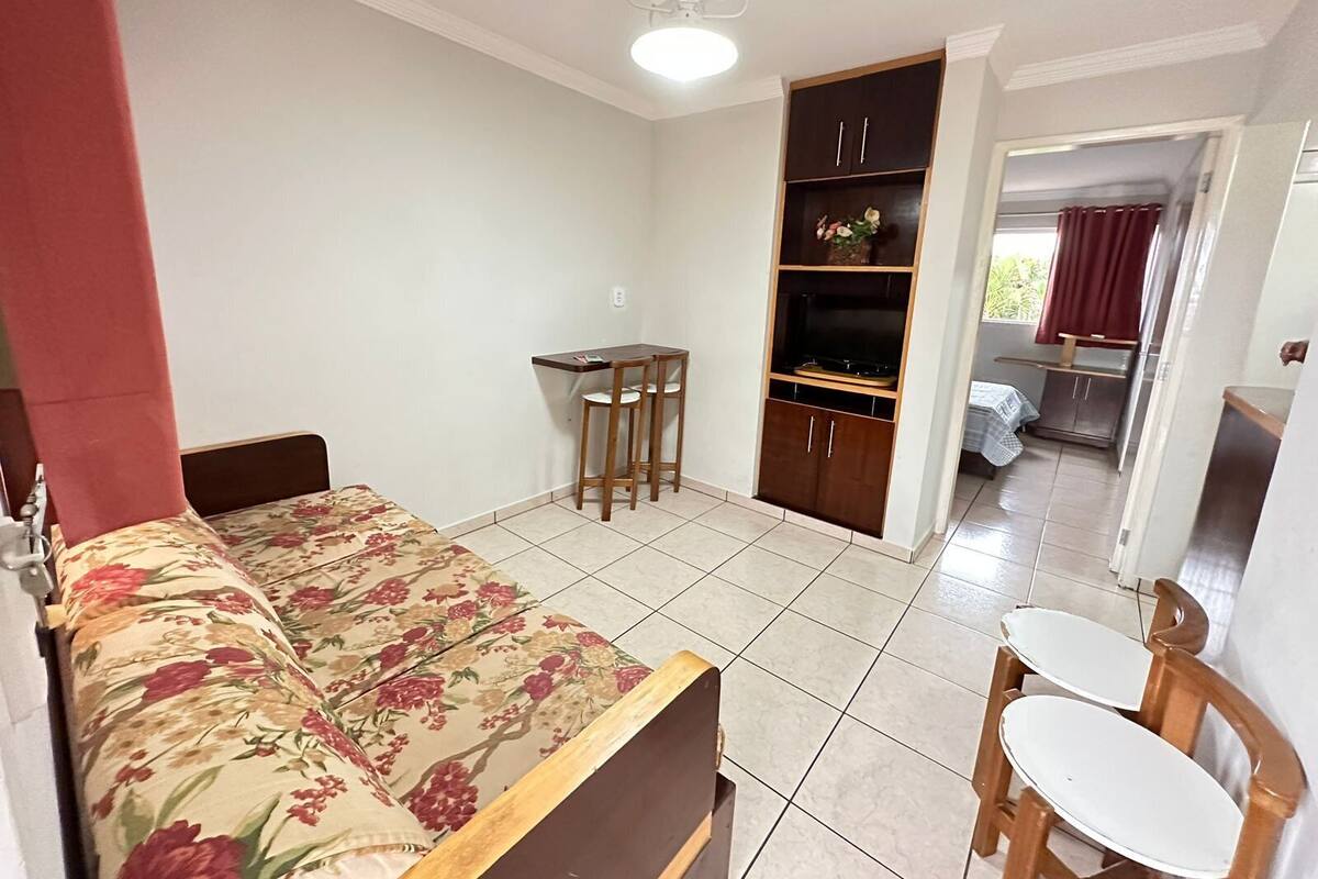 A bedroom with a bed, a desk, a wardrobe, and a small table.