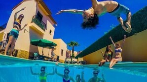 Una piscina con gente en el agua y en el borde.
