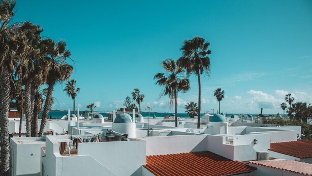 Un hotel costero con edificios blancos, techos de tejas rojas y palmeras.