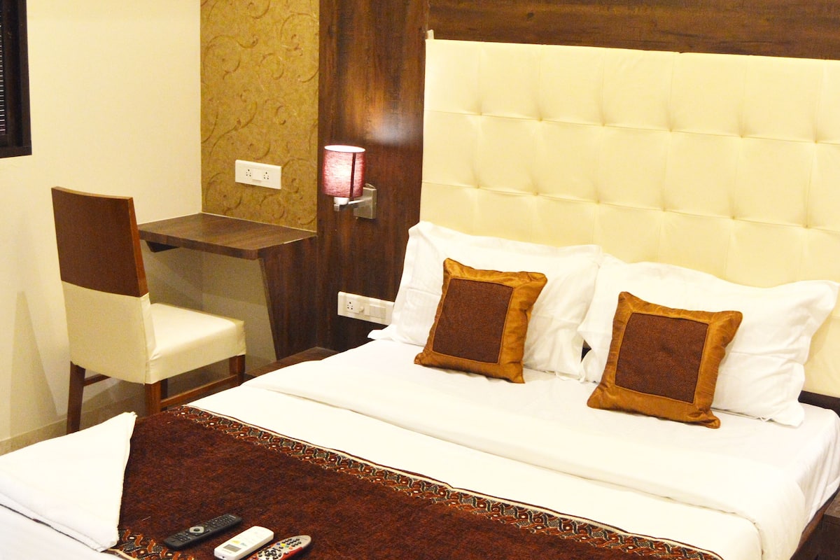 A hotel room with a large bed, a desk, and a chair.