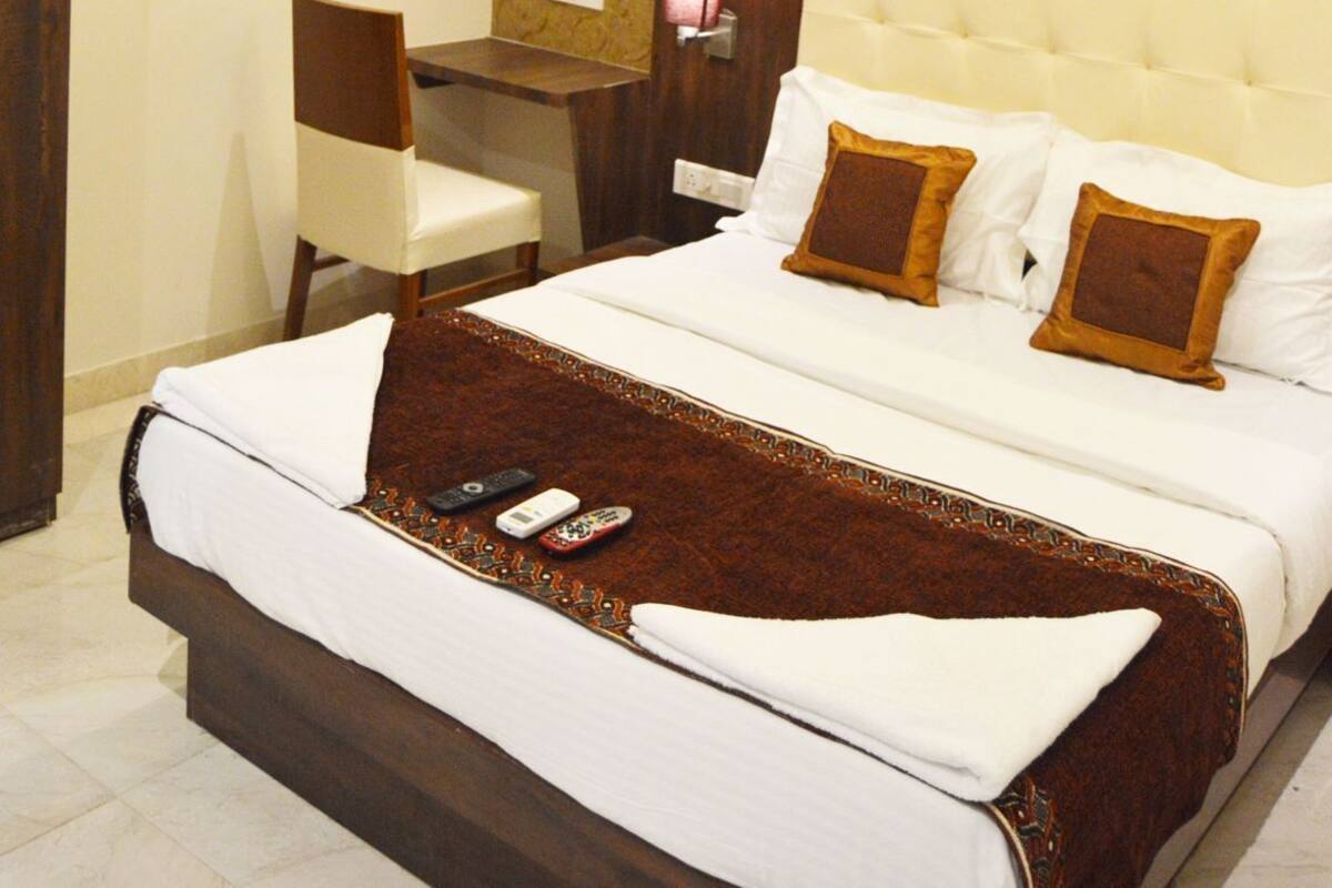 A hotel room with a bed, a desk, a chair, a ceiling fan, and an air conditioning unit.
