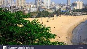A coastal cityscape with a sandy beach and dense urban buildings in the background. - Hotel AK International (Mumbai)