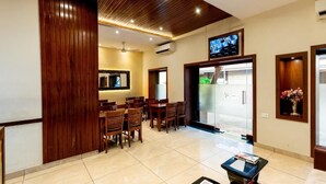 A hotel lobby with wooden paneling, a reception desk, and a television mounted on the wall. - Hotel AK International (Mumbai)