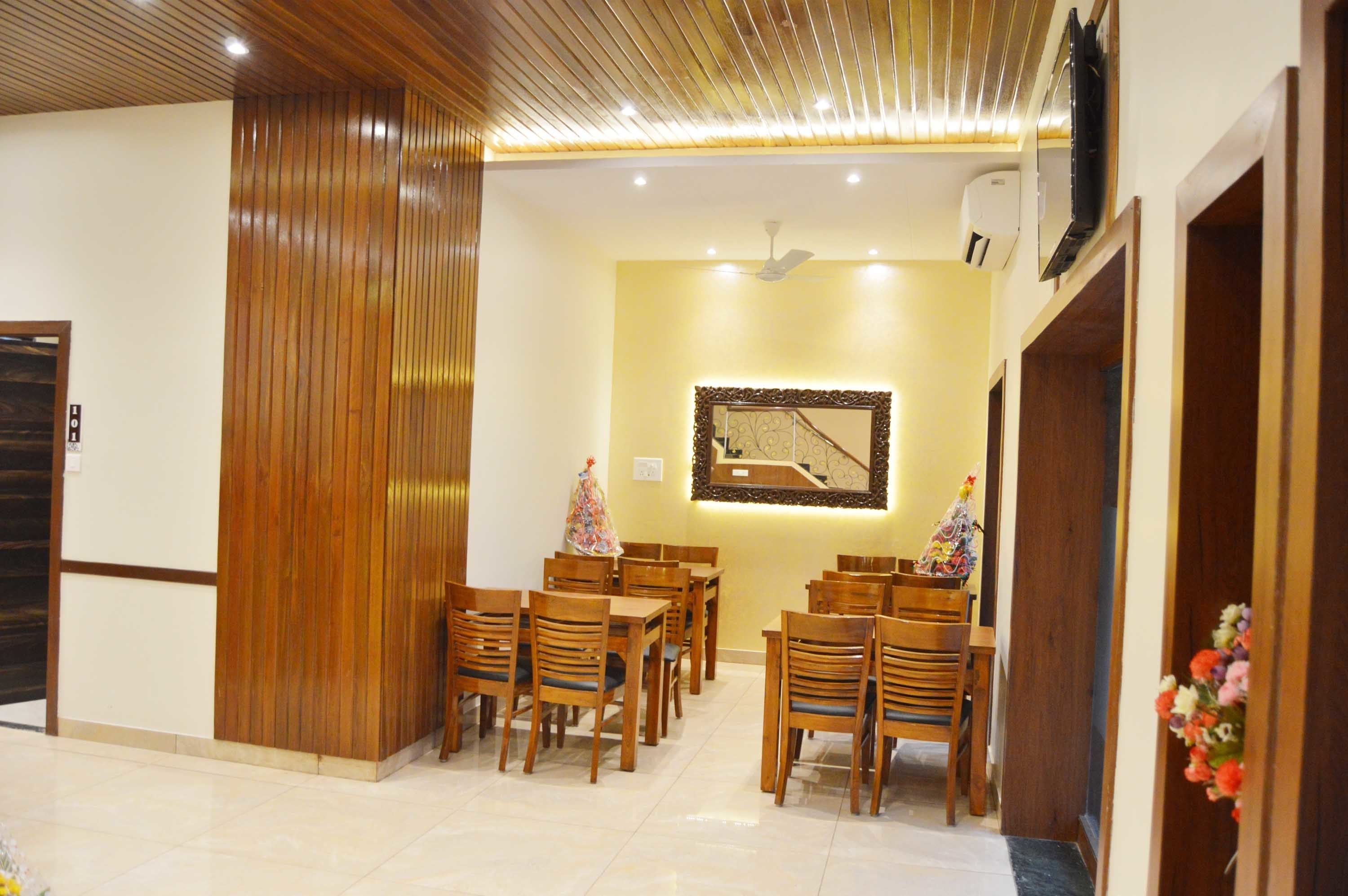 Un espace repas avec des tables et des chaises en bois, un ventilateur de plafond et un climatiseur fixé au mur.