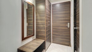 A modern bathroom with a wooden vanity, a large mirror, and a shower area. - Hotel AK International (Mumbai)