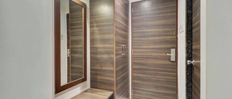 Un baño moderno con tocador de madera, un espejo grande y zona de ducha.