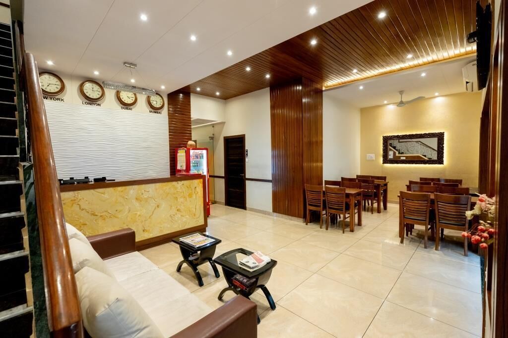 A hotel lobby with a reception desk, seating area, and clocks on the wall.