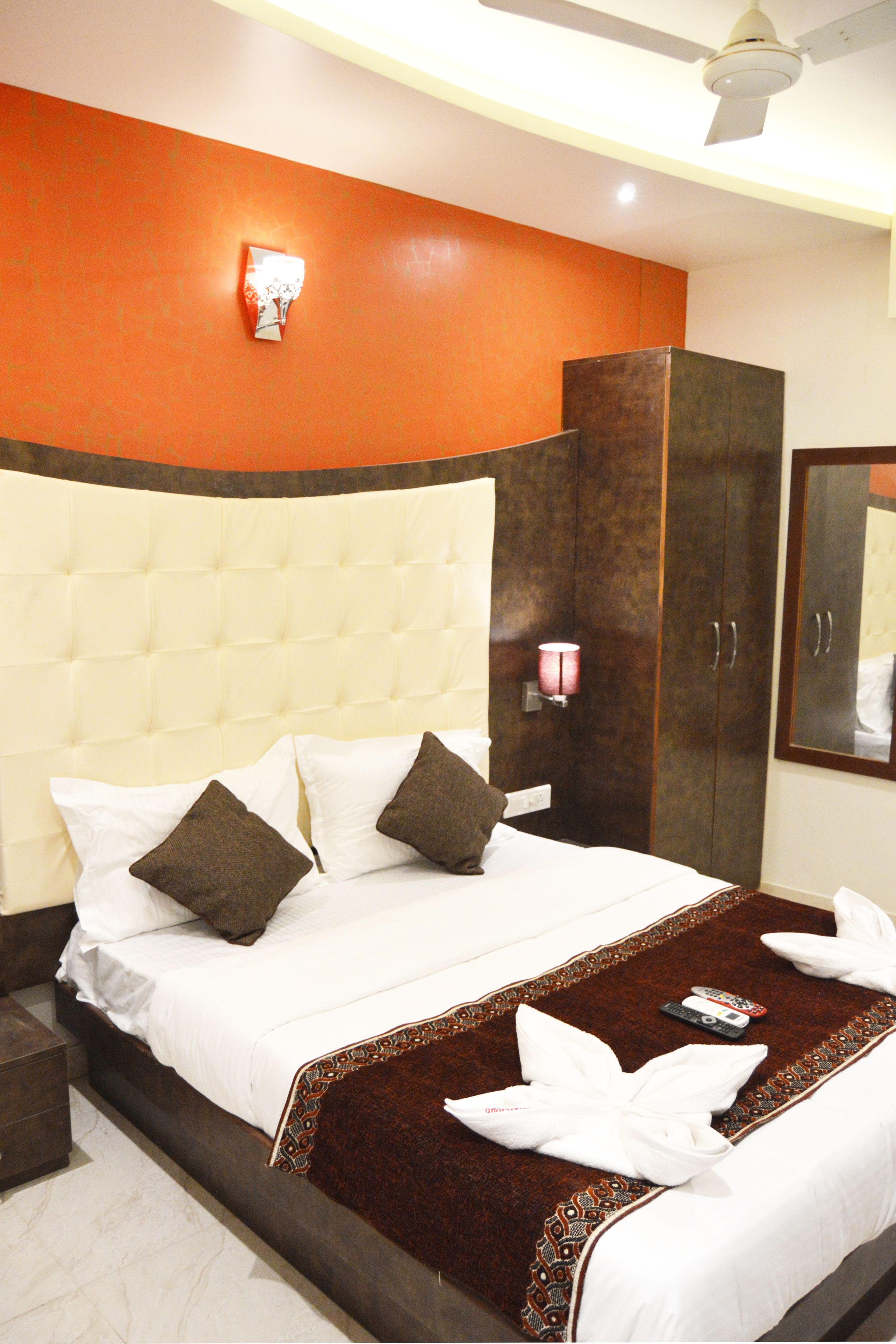 A hotel room with a large bed, a wardrobe, and a mirror.