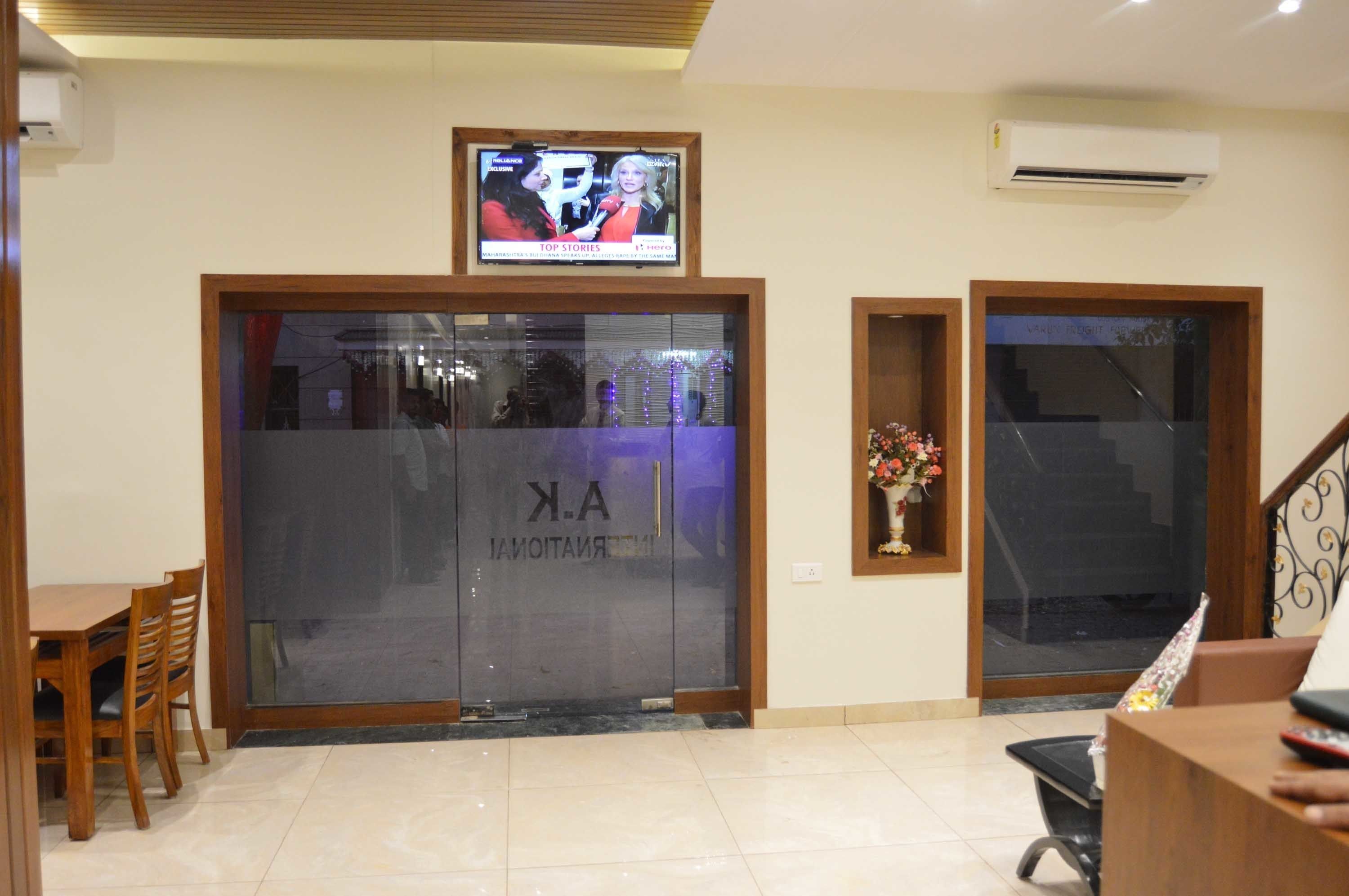 A reception area with a TV displaying 'Top Stories', a glass door entrance, a reception desk, and a staircase.