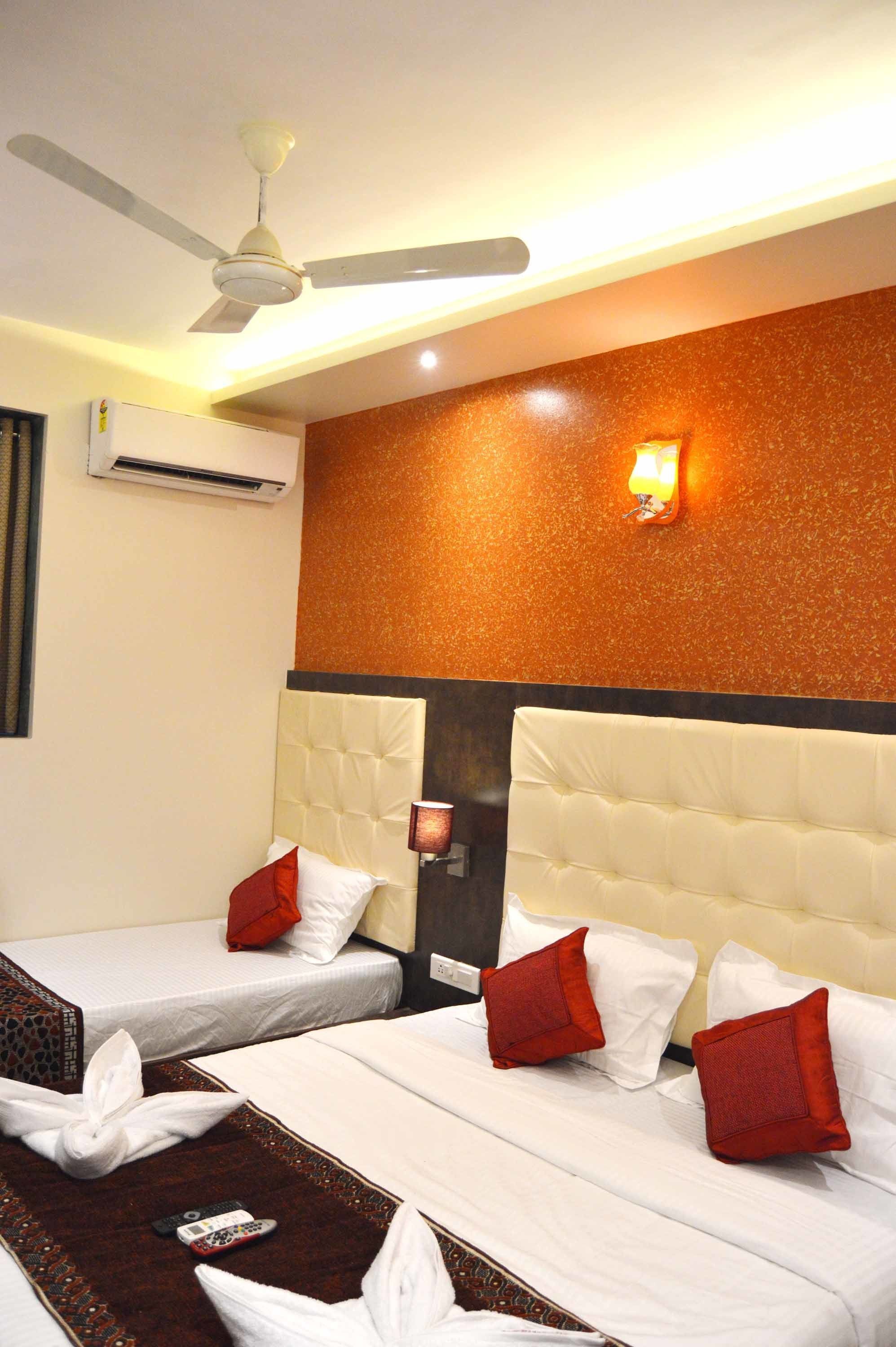 Une chambre d’hôtel avec deux lits, un ventilateur de plafond, un climatiseur et un luminaire fixé au mur.