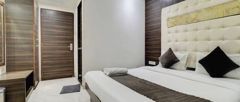 A modern bedroom with a large bed, wooden wardrobe, and a wall-mounted air conditioner.